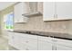 Contemporary kitchen featuring white cabinets, black countertops, and stainless steel vent hood at 10432 Torchwood Sea Way, San Antonio, FL 33576