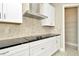 Modern kitchen featuring stainless steel appliances, black countertop, white cabinets, and a stylish exhaust hood at 10432 Torchwood Sea Way, San Antonio, FL 33576