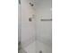 All-white tiled stand-up shower with glass door, shower head, and grab bar at 128 Nancy Dr # 128, Oldsmar, FL 34677