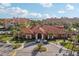Stunning aerial view of the clubhouse with a brick drive and beautiful landscaping, plus water views from the community at 2713 Via Murano # 216, Clearwater, FL 33764