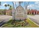 Community entrance with stone monument, decorative details, and manicured flower beds for a luxurious welcome at 2713 Via Murano # 216, Clearwater, FL 33764