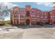 Attractive red condo building featuring covered garages and well-kept grounds with palm trees at 2713 Via Murano # 216, Clearwater, FL 33764