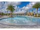 Beautiful community pool with palm trees, lounge chairs, umbrellas, and a white pool house under a partly cloudy sky at 32960 Regent Canal St, Wesley Chapel, FL 33545