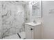 Updated bathroom features marble-look shower tile, and white vanity, creating a sleek design at 3620 E Shadowlawn Ave, Tampa, FL 33610