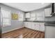 Modern kitchen with white cabinetry, granite countertops, stainless steel sink, and wood look flooring at 3620 E Shadowlawn Ave, Tampa, FL 33610