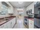 Functional kitchen featuring white cabinets, stainless steel appliances, and neutral-toned backsplash and flooring at 36936 Kay Ave, Zephyrhills, FL 33542