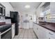 Functional kitchen featuring white cabinetry, stainless steel appliances, and neutral-toned backsplash and flooring at 36936 Kay Ave, Zephyrhills, FL 33542