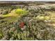 An aerial view with a red marker showcasing property nestled among trees and neighboring houses in a green, expansive area at 38506 Higginson Rd, Zephyrhills, FL 33540