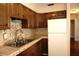 An open kitchen shows dark cabinets, a stainless sink, and a white refrigerator at 4355 Tahitian Gardens Cir # D, Holiday, FL 34691