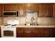 Close-up of kitchen showcasing tiled backsplash, double basin sink, and white stove at 4355 Tahitian Gardens Cir # D, Holiday, FL 34691