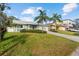 Charming single-story home featuring a lush green lawn, mature palm trees, and a well-maintained landscape at 45 Gulfwinds W Dr, Palm Harbor, FL 34683
