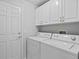 Bright laundry room featuring a washer, dryer, and white storage cabinets at 45 Gulfwinds W Dr, Palm Harbor, FL 34683