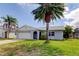 Charming single-story home with a well-maintained lawn, mature palm trees, and attached two car garage at 7034 Southwind Dr, Hudson, FL 34667