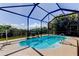 Screened-in pool with chairs for relaxing, featuring a safety handrail and lovely landscaping in the background at 7034 Southwind Dr, Hudson, FL 34667