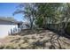 View of the backyard with mature trees, grass, a fence line, and the rear of the house at 7144 Fairfax Dr, Port Richey, FL 34668