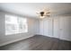 Bedroom with gray wood-look flooring, closet, white trim, and a ceiling fan at 7144 Fairfax Dr, Port Richey, FL 34668