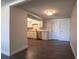 Open-concept kitchen with stainless appliances, white shaker cabinets, and modern flooring adjacent to a large space at 7144 Fairfax Dr, Port Richey, FL 34668