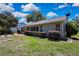 Side view of the home with a patio, trimmed shrubs, and well-kept lawn at 8045 Sugarbush Dr, Spring Hill, FL 34606