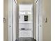 Hallway view of a spacious bathroom with double sinks, white cabinets, and tiled flooring at 8045 Sugarbush Dr, Spring Hill, FL 34606