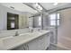 Bright bathroom featuring double sinks, white cabinets, large mirror, and a shower with glass door at 8045 Sugarbush Dr, Spring Hill, FL 34606