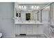 Bright bathroom featuring double sinks, white cabinets, large mirror, shower stall, and tiled flooring at 8045 Sugarbush Dr, Spring Hill, FL 34606