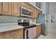 Contemporary kitchen with stainless steel appliances, mosaic backsplash, and wood cabinetry at 8045 Sugarbush Dr, Spring Hill, FL 34606