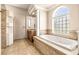 Bathroom featuring a soaking tub, decorative tile, and glass block window at 10364 Locker Dr, Spring Hill, FL 34608