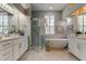 Beautiful bathroom boasts double vanities, a modern soaking tub, and glass-enclosed shower at 10614 Chambers Dr, Tampa, FL 33626