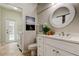 Stylish bathroom with white cabinetry, round mirror, and decor, plus a door leading to pool at 10614 Chambers Dr, Tampa, FL 33626