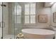 Elegant bathroom with a glass shower, tub, and window with plantation shutters at 10614 Chambers Dr, Tampa, FL 33626