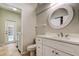 Well-lit bathroom with white vanity, decorative mirror, and view to pool area at 10614 Chambers Dr, Tampa, FL 33626