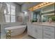 Bright bathroom with a freestanding tub next to a marble wall and a vanity with a white countertop at 10614 Chambers Dr, Tampa, FL 33626