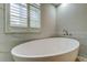 Close up of a luxurious modern bathtub with white marble and a window with shutters at 10614 Chambers Dr, Tampa, FL 33626