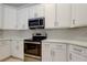 Close up of kitchen showcasing stainless steel appliances, white cabinets, and quartz countertops at 10614 Chambers Dr, Tampa, FL 33626