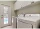 Laundry room with white washer, dryer and cabinets, featuring access door to the pool area at 10614 Chambers Dr, Tampa, FL 33626