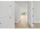 Hallway with luxury vinyl plank flooring and white walls, leading to a living space with natural light at 11885 Richmond Trl, Parrish, FL 34219