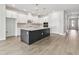 Bright open kitchen with white cabinets, stainless steel appliances, dark island, and light wood-look floors at 11885 Richmond Trl, Parrish, FL 34219