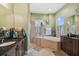 Spacious bathroom featuring dual vanities, a glass-enclosed shower, and a luxurious soaking tub with decor at 1514 River Ct, Tarpon Springs, FL 34689