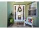 Charming front porch with a white door, decorative wreath, and a cozy bench with a colorful pillow at 1514 River Ct, Tarpon Springs, FL 34689