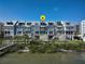 Waterfront townhouses with balconies, stairs to the entrances, and coastal landscaping on a sunny day at 19915 Gulf Blvd # 704, Indian Shores, FL 33785