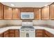 Galley kitchen features a stove top, white microwave, and wooden cabinets at 2122 Hailstone Cir, Sun City Center, FL 33573