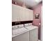 Laundry room with side-by-side white washer and dryer and white storage cabinets at 2439 Hidden Trail Dr, Spring Hill, FL 34606