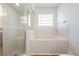 Bathroom showcasing a tiled tub, separate shower with glass door, and a window at 29443 Zeller Ave, San Antonio, FL 33576