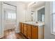 Bathroom featuring dual sinks, wood-look flooring, and separate tub/shower area at 29443 Zeller Ave, San Antonio, FL 33576