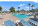 Community pool featuring lounge chairs, tables, and umbrellas with palm trees in the background at 29443 Zeller Ave, San Antonio, FL 33576