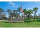 Entrance sign to Tampa Bay Golf & Country Club with palm trees, landscaping, and an American flag at 29443 Zeller Ave, San Antonio, FL 33576