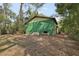 Back of a two-story green house surrounded by trees and leaves at 303 Grand Ave, Brooksville, FL 34604