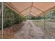 Exterior shot of a covered carport and dirt driveway leading to the property at 303 Grand Ave, Brooksville, FL 34604
