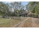 Quaint green home with a fenced yard, covered porch, and detached carport at 303 Grand Ave, Brooksville, FL 34604