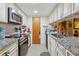 A functional kitchen features granite counters, wood floors, stainless steel appliances, and classic white cabinetry at 303 Grand Ave, Brooksville, FL 34604